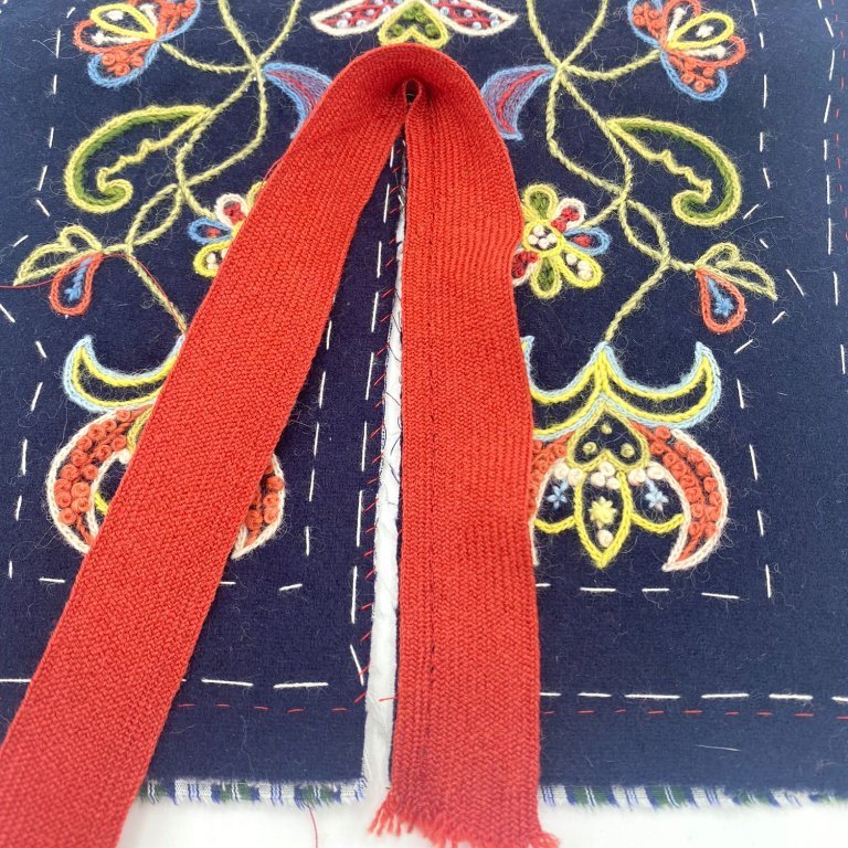 Klaufin er brydduð fyrst. Leggið bryddinguna á réttuna, hafið ávallt augun á brún klaufarinnar. Saumið bryddinguna á með nokkuð þéttum aftursting. Athugið að það getur reynst vandasamt að sauma niður bryddinguna í kverkinni. Reynið að brjóta vasann saman á þann máta að hægt sé að sauma bryddinguna áfram flata við. Þegar búið er að sauma bryddinguna við á hún að standa upprétt í kverkinni.