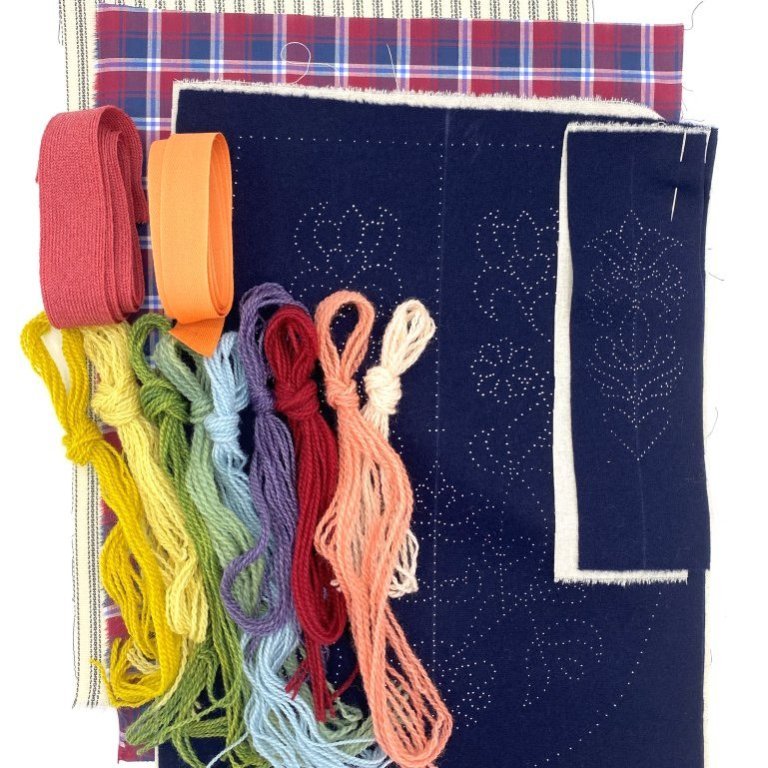 Each kit contains two printed wool fabrics, calico backing fabric, cotton lining for the front piece, thick cotton fabric for the back, wool binding for the edges, wool embroidery thread and a needle. Other notions that are not included but needed are a good pair of scissors and sewing thread in a bright colour.