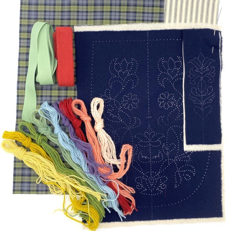Each kit contains two printed wool fabrics, calico backing fabric, cotton lining for the front piece, thick cotton fabric for the back, wool binding for the edges, wool embroidery thread and a needle. Other notions that are not included but needed are a good pair of scissors and sewing