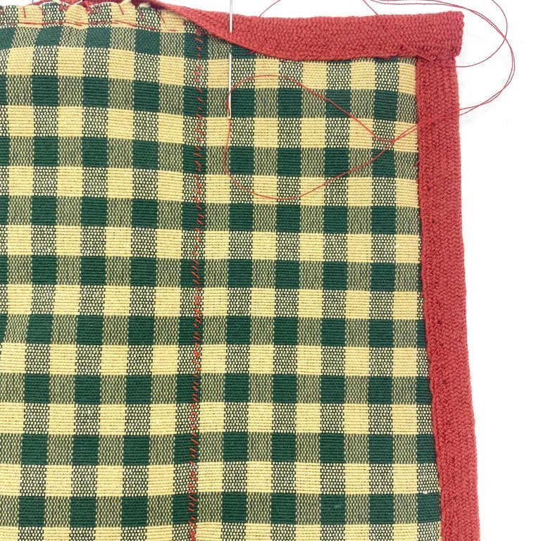 Bind the top edge of the pocket and secure the ends by folding them in under the binding.